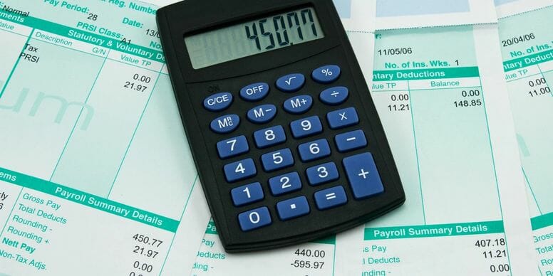 calculator laying on top of a stack of payroll statements