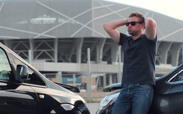 upset man standing next to car after car accident